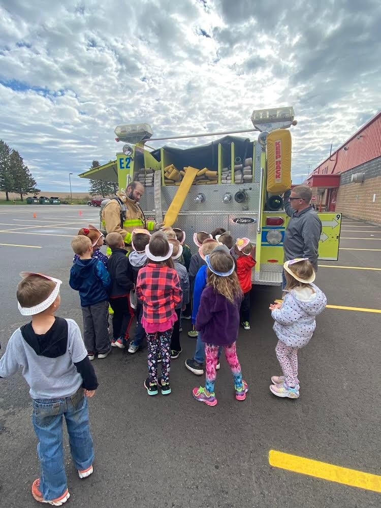 students looking at hoses on firetruck  