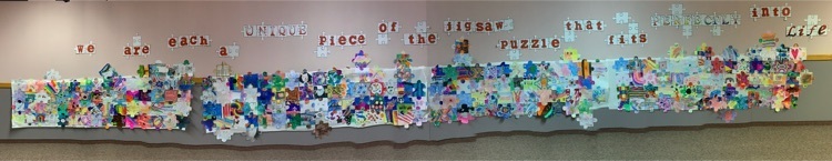 panoramic photo of students jigsaw pieces that go into a wall mural. ￼